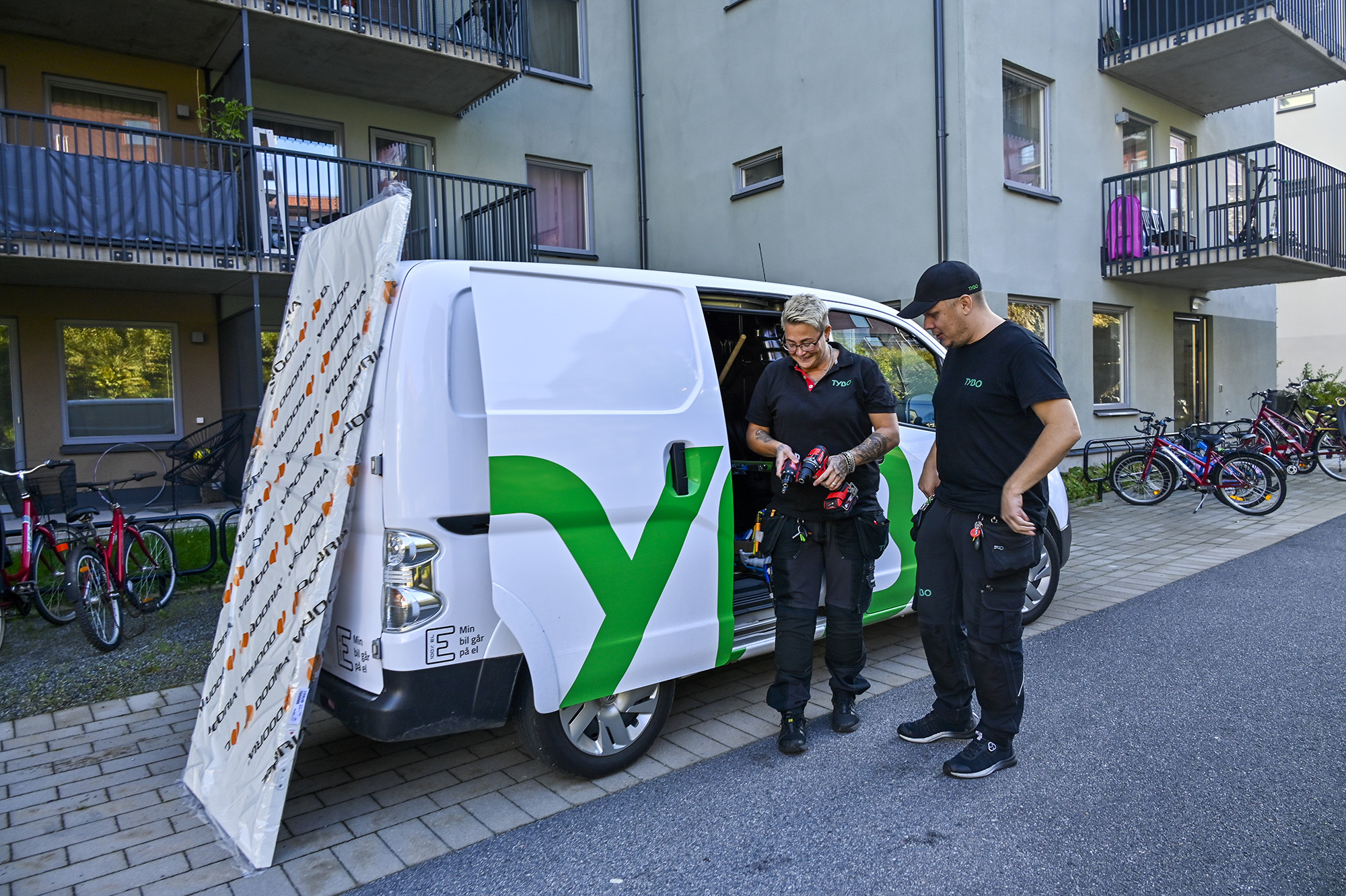 Fastighetsvärdar planerar dagens arbete vid en skåpbil med Tybos logotyp.