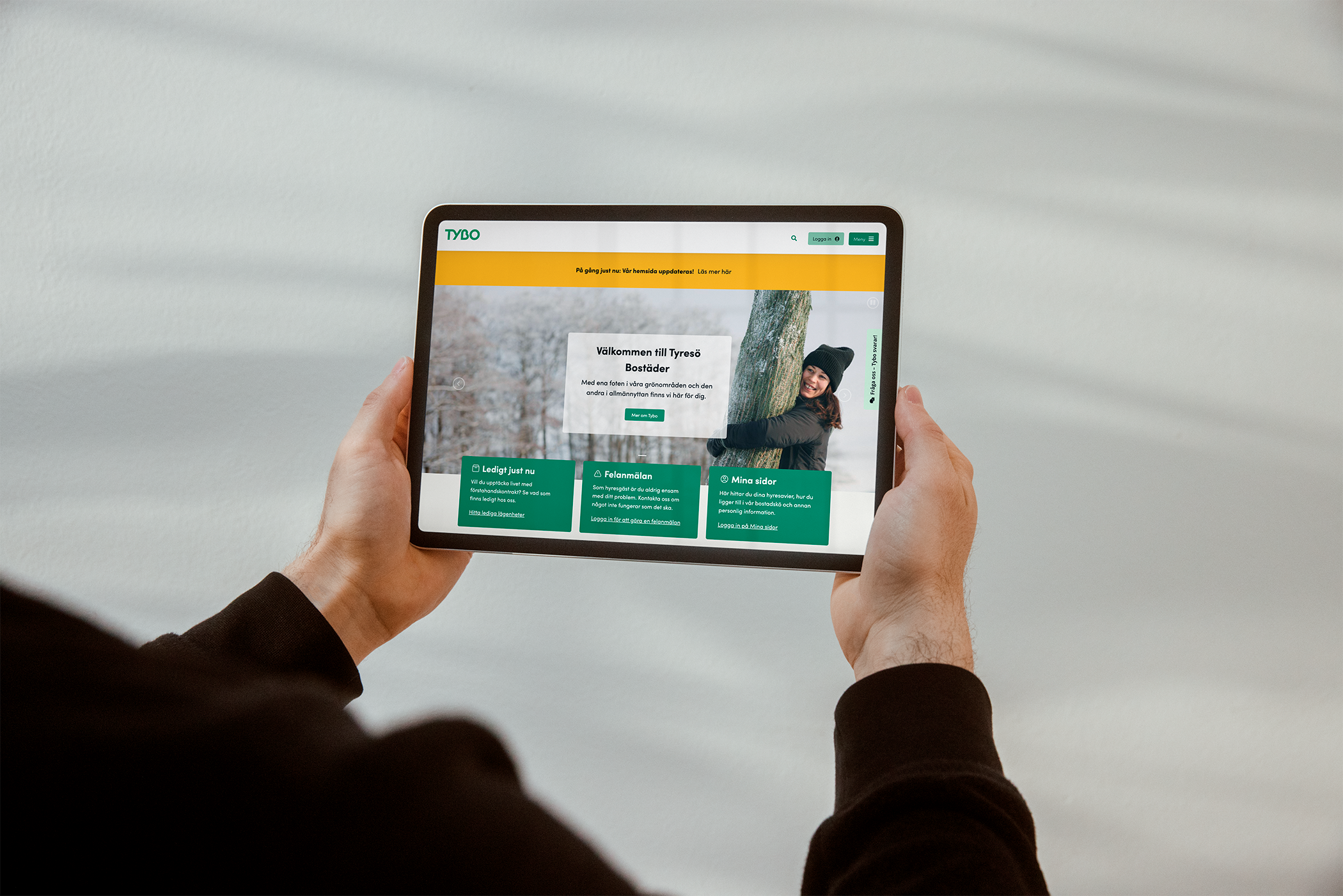 En kvinna håller upp en ipad som visar Tyresö Bostäders hemsida
