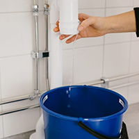 Bild på en hink som står under vattenlåset under handfatet.