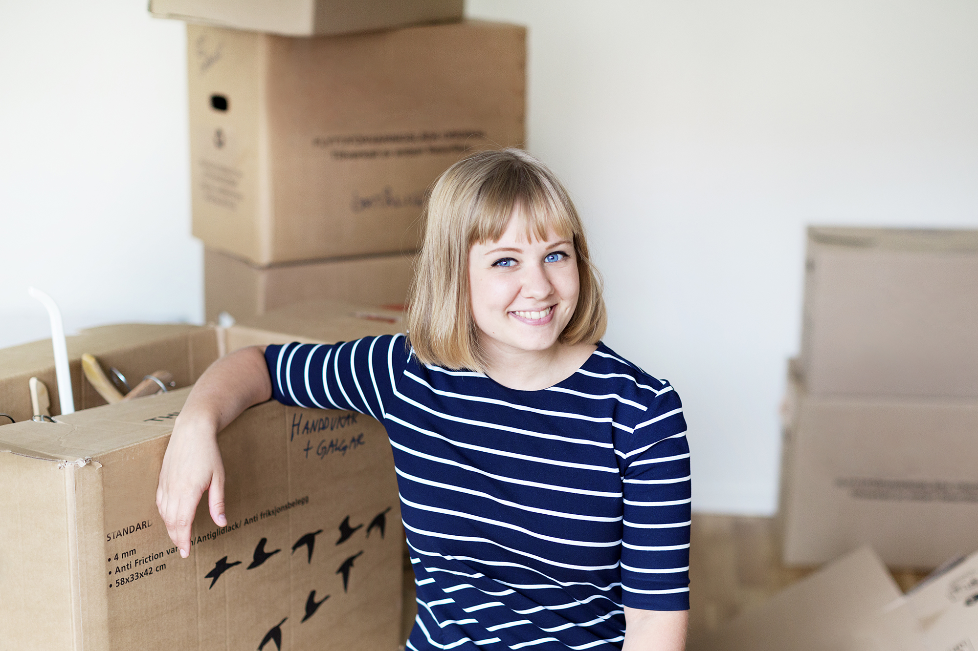 Glad ung kvinna bland flyttkartonger