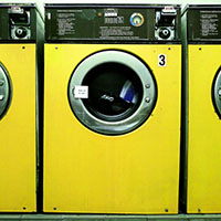 bild på gula tvättmaskiner i en tvättstuga.